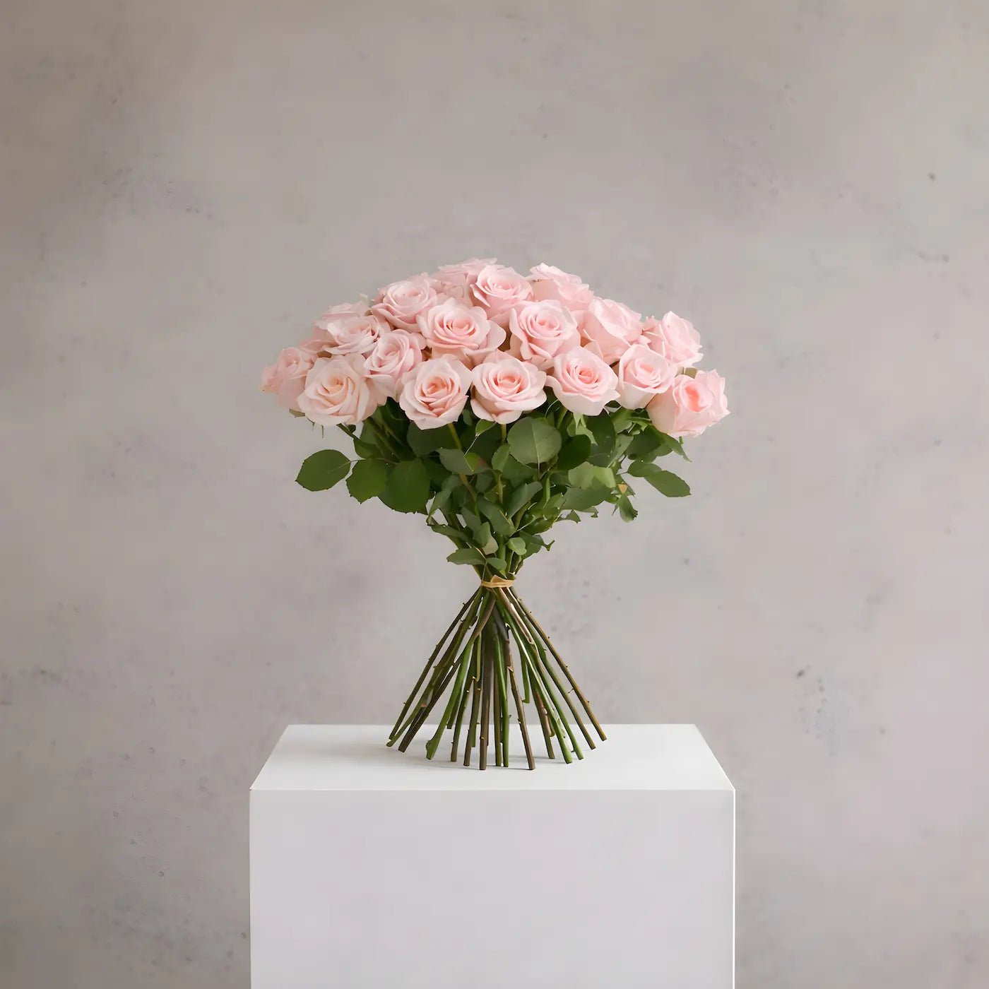 Bouquet of pink roses on a white pedestal against a gray background