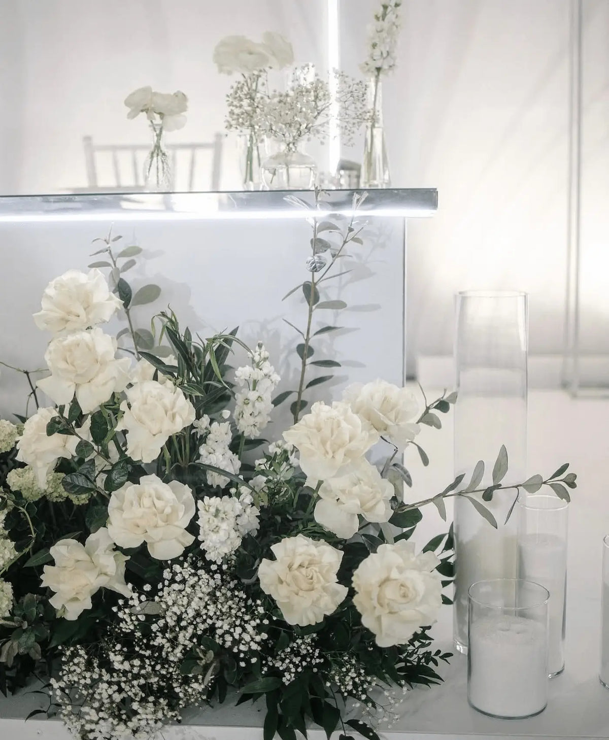 Modern white floral installation with roses and hydrangeas in a clear display