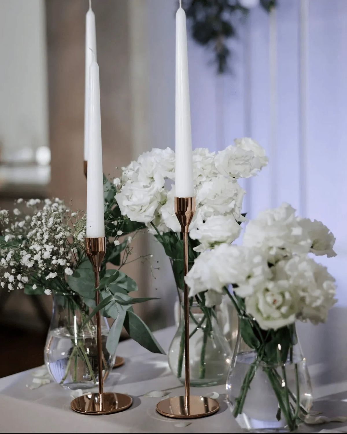Elegant table centerpiece with white florals and candles for a wedding reception