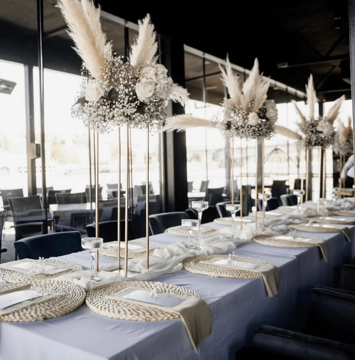 Long banquet wedding table styled with neutral linens and elevated floral designs