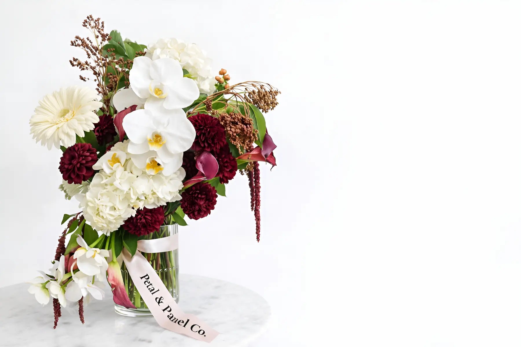 Luxury floral arrangement by Petal & Panel Co., an Ann Arbor florist, featuring orchids and seasonal blooms in a modern glass vase