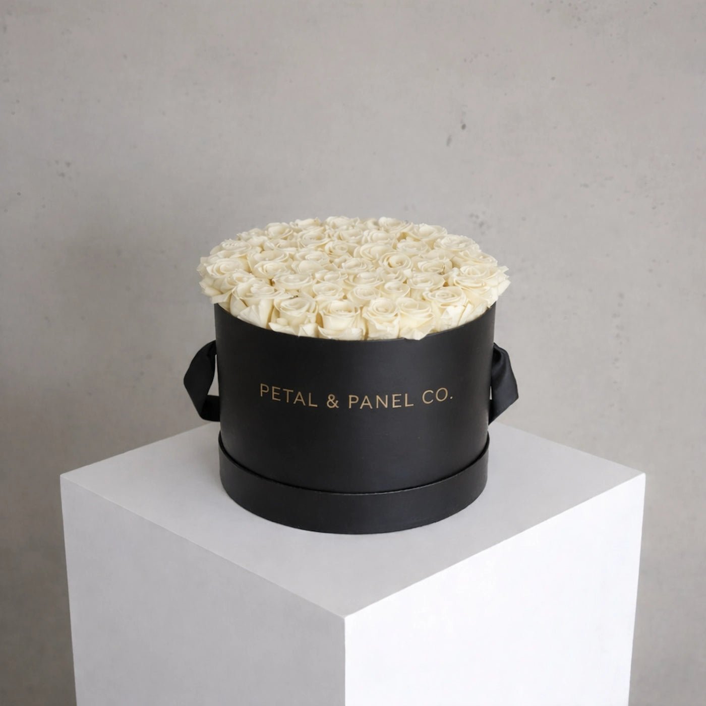 Black round box with white flowers on a gray background