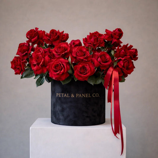 Bouquet of red roses in a black box with a red ribbon on a gray background