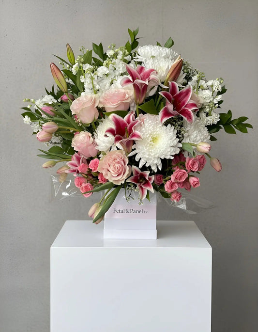 Bouquet of pink and white flowers on a white pedestal against a gray background