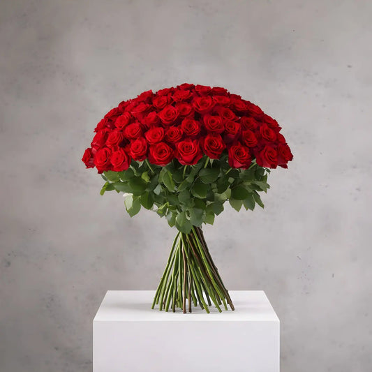 Bouquet of red roses on a white pedestal against a gray background