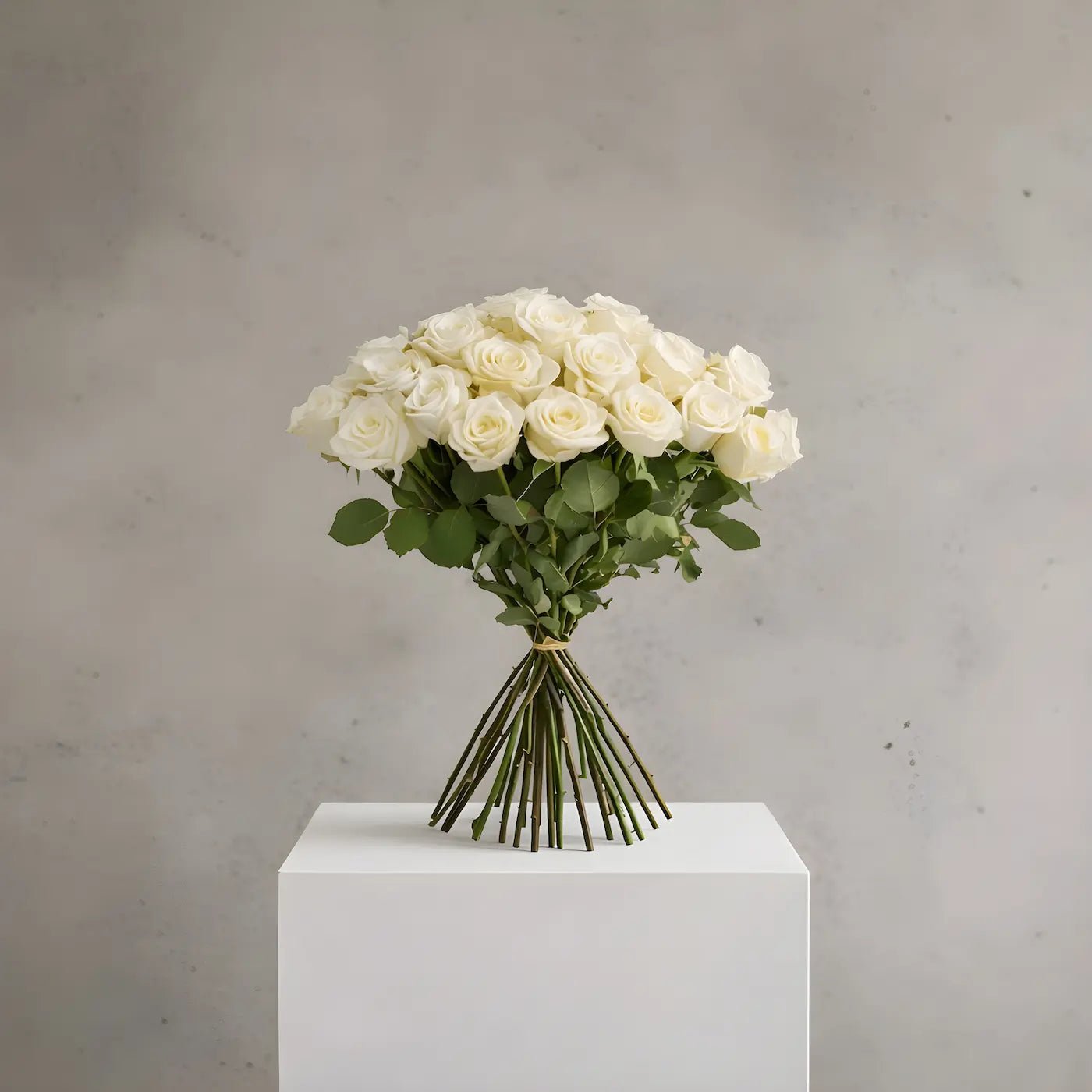 Bouquet of white roses on a white pedestal against a gray background