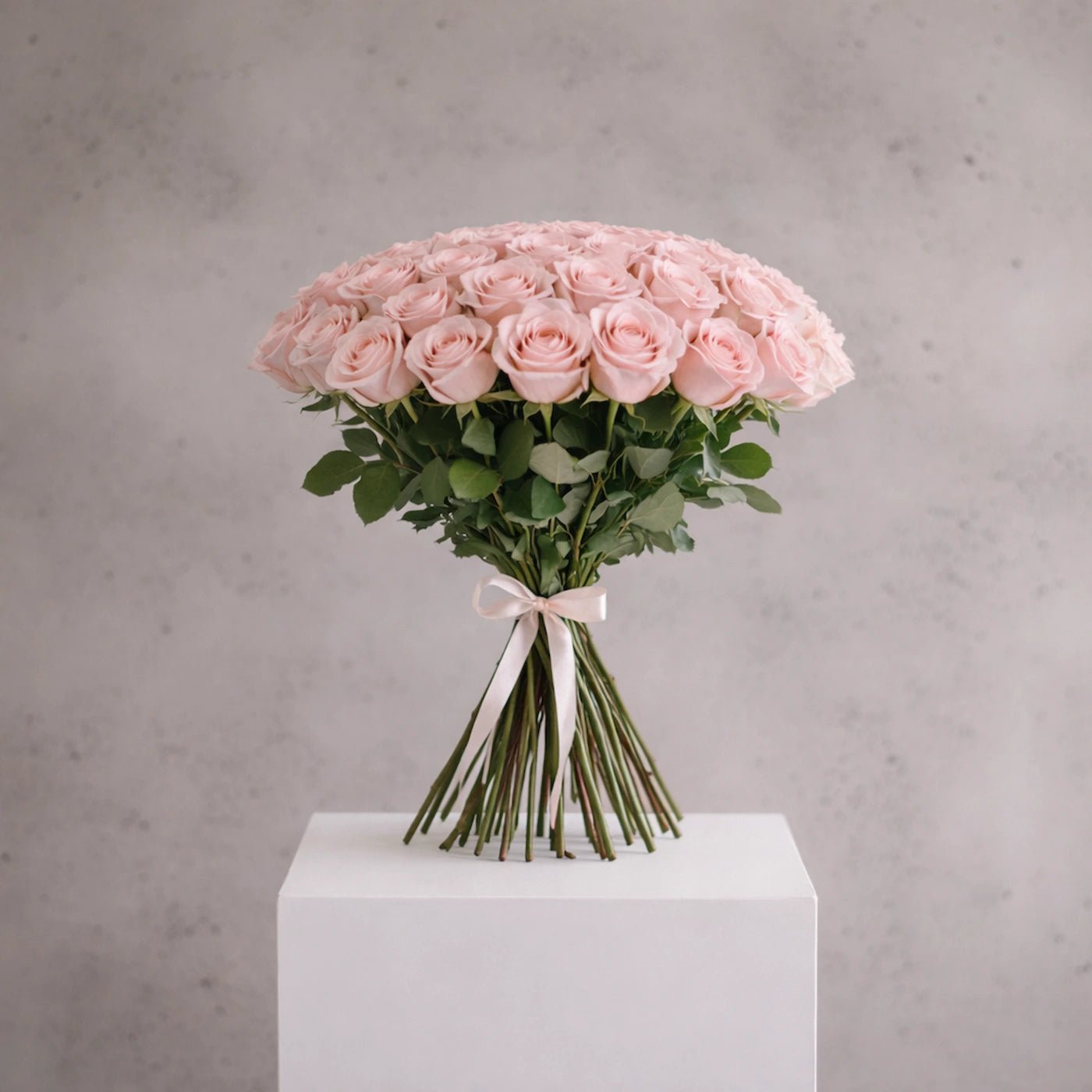 Bouquet of pink roses on a white pedestal with a gray background