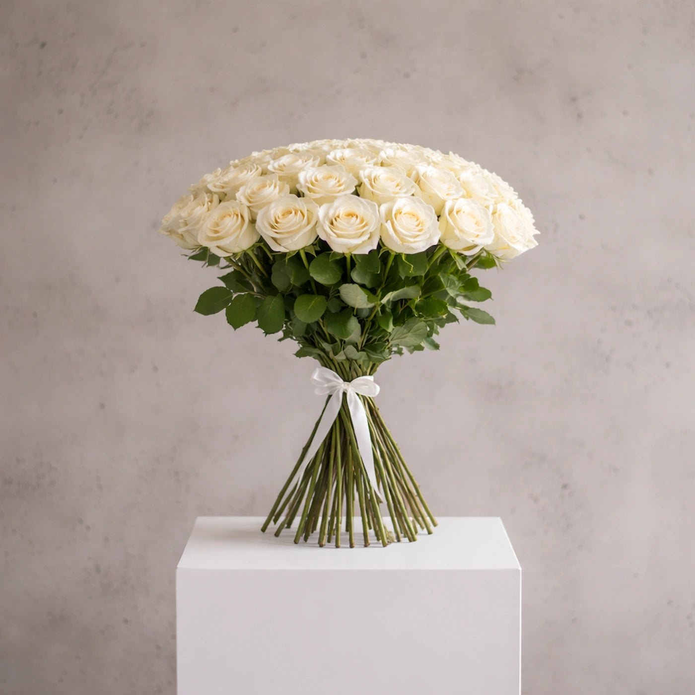 Bouquet of white roses on a white pedestal against a gray background