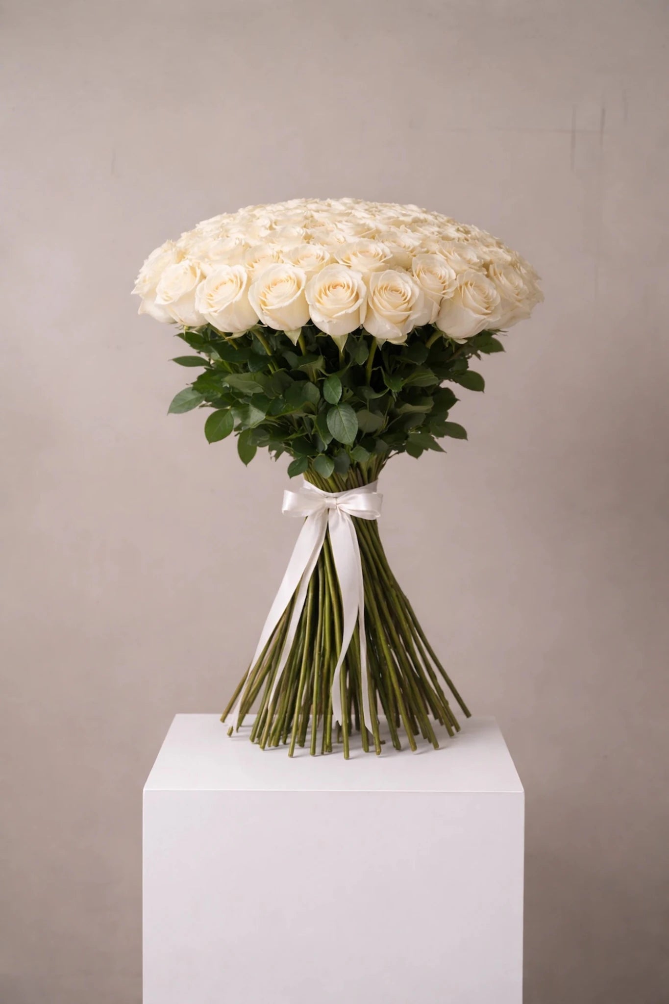 Bouquet of white roses on a white pedestal against a gray background