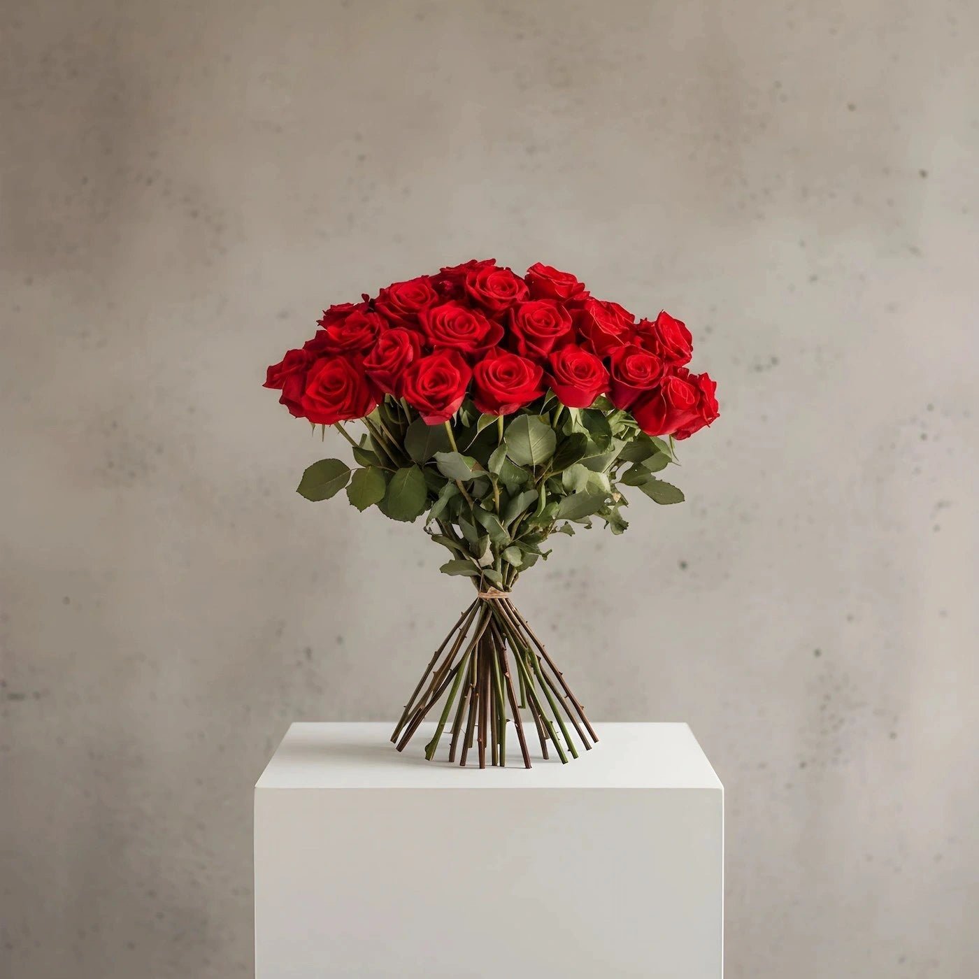 Bouquet of red roses on a white pedestal against a gray background