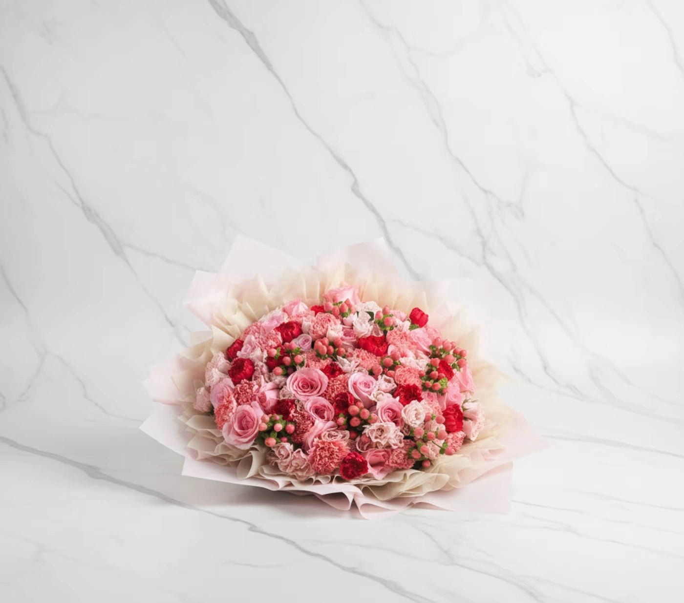 Bouquet of pink and red flowers on a white bedspread