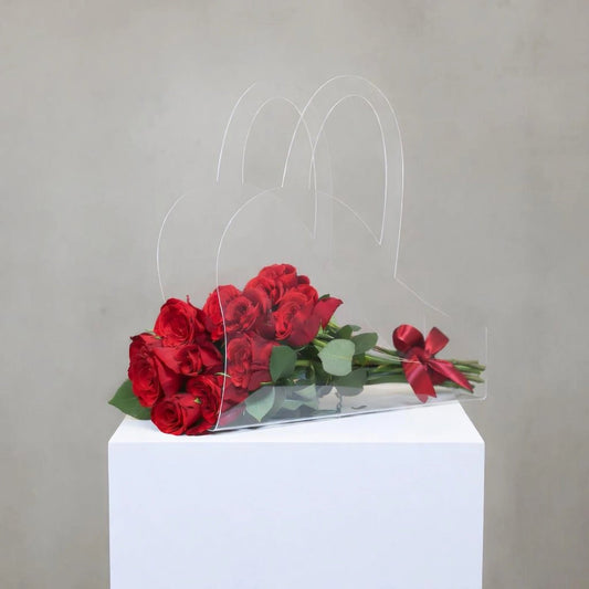 Clear acrylic stand with red roses on a white pedestal against a gray background