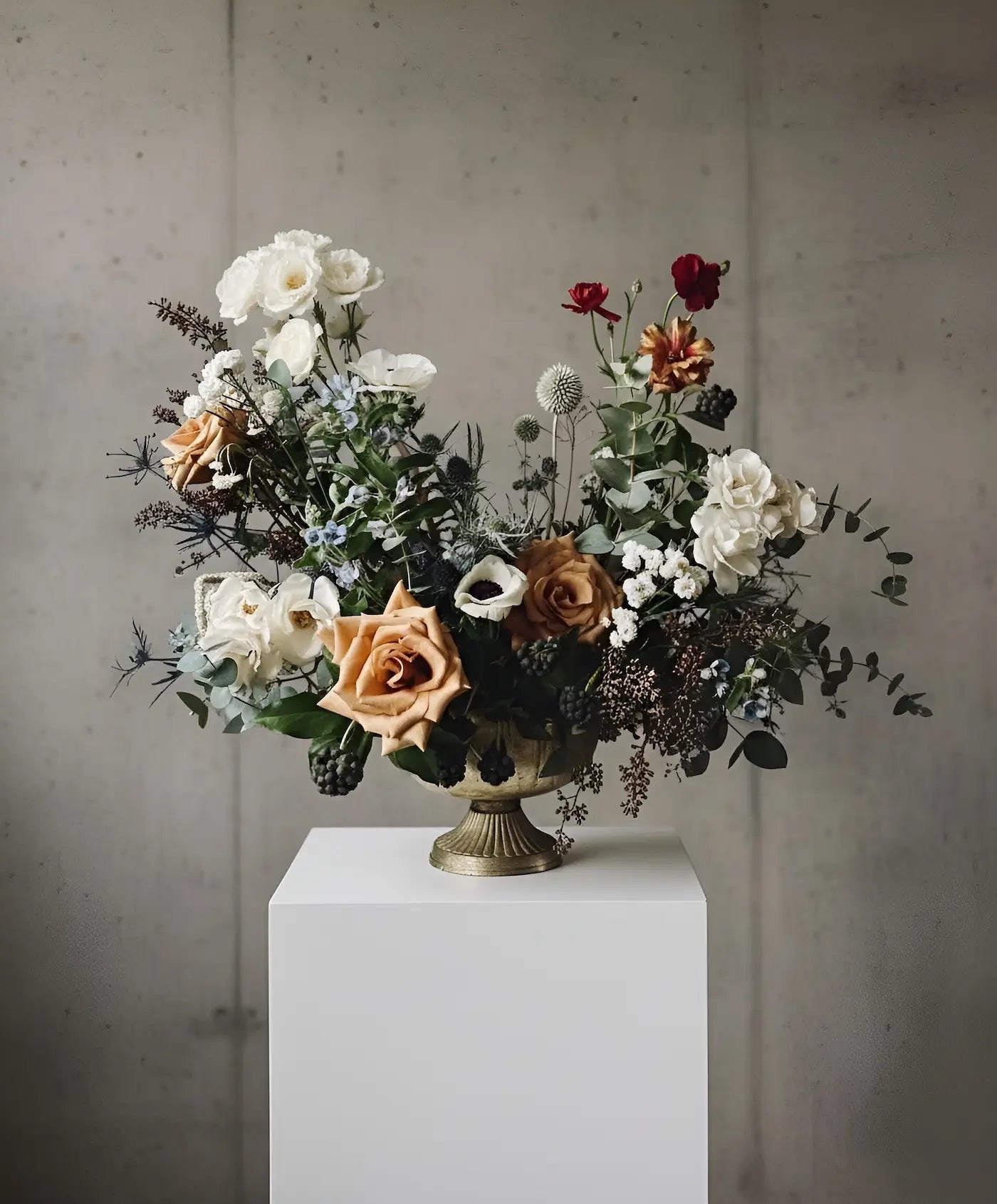 Floral arrangement in a vase on a white pedestal against a gray wall