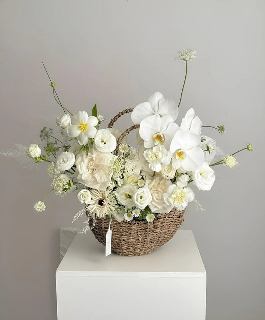 Basket of white flowers on a white pedestal against a gray background